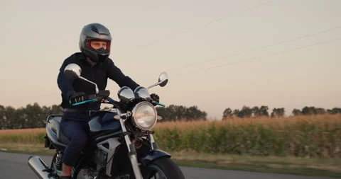 A young biker in black clothes rides along the fields of corn. Evening, the moon Stock Footage 277093556