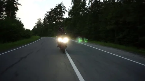 A young biker in a leather jacket and a helmet riding at the motorcycle along Stock Footage 83484957