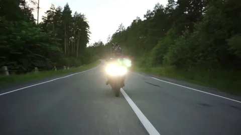 A young biker in a leather jacket and a helmet riding at the motorcycle along Stock Footage 83484971
