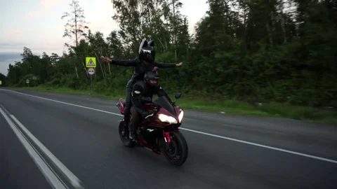 A young biker in a leather jacket and a helmet riding at the motorcycle along Stock Footage 83485302