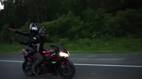 A young biker in a leather jacket and a helmet riding at the motorcycle along Stock Footage 83548895