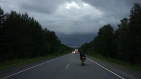 A young biker in a leather jacket and a helmet riding at the motorcycle along Stock Footage 83548901