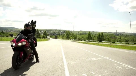 A young biker in a leather jacket and a helmet riding at the motorcycle along Stock Footage 83549428