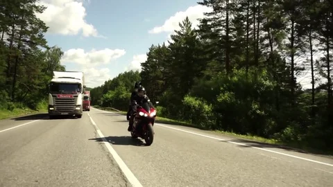 A young biker in a leather jacket and a helmet riding at the motorcycle along Stock Footage 83549460