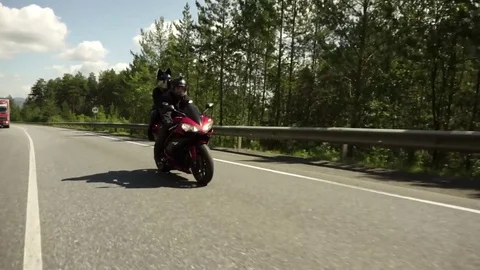 A young biker in a leather jacket and a helmet riding at the motorcycle along Stock Footage 83549502
