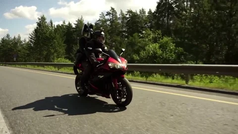 A young biker in a leather jacket and a helmet riding at the motorcycle along Stock Footage 83549542