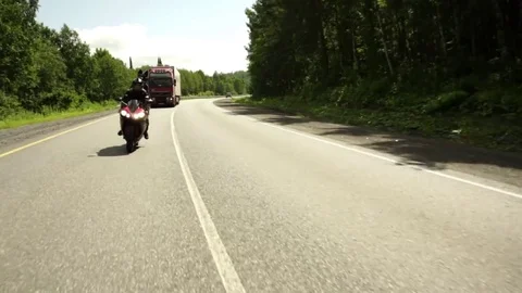 A young biker in a leather jacket and a helmet riding at the motorcycle along Stock Footage 83590823