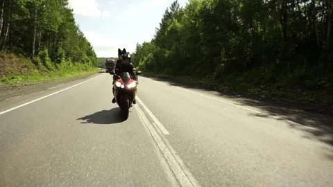 A young biker in a leather jacket and a helmet riding at the motorcycle along Stock Footage 83590834