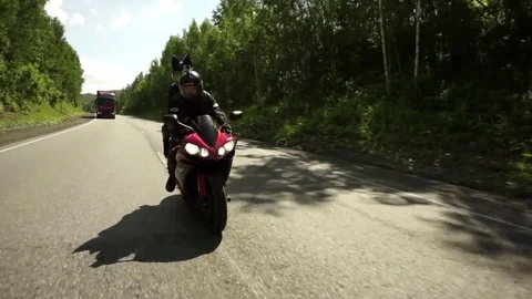 A young biker in a leather jacket and a helmet riding at the motorcycle along Stock Footage 83590844