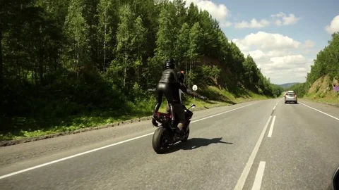 A young biker in a leather jacket and a helmet riding at the motorcycle along Stock Footage 83590856