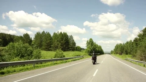 A young biker in a leather jacket and a helmet riding at the motorcycle along Stock Footage 83705508