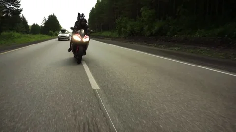 A young biker in a leather jacket and a helmet riding at the motorcycle along Stock Footage 83705526