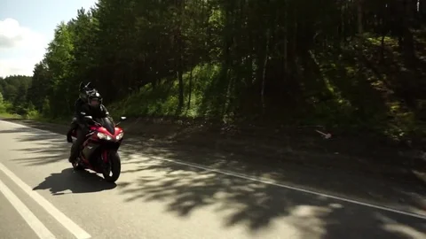 A young biker in a leather jacket and a helmet riding at the motorcycle along Stock Footage 83705533
