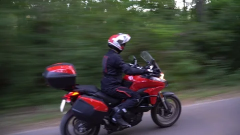 Young biker riding motorcycle through forest road. Steady gimbal shot. 4K. Video stock 111617251