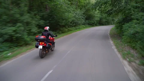 Young biker riding motorcycle through forest road. Steady gimbal shot. 4K. Stock Footage 111617339