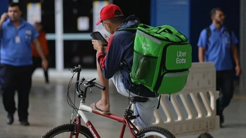 Young biker for Uber Eats wearing a medical face mask during the Covid-19 Stock Footage 127209788