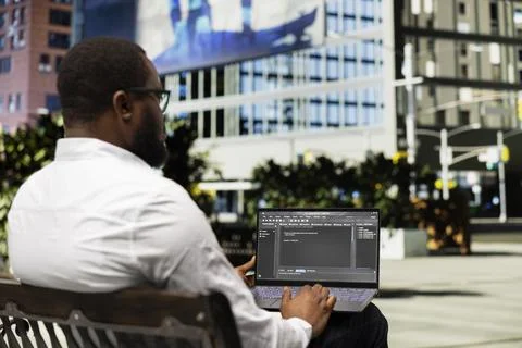 Young black adult programming binary code on terminal window 库存照片