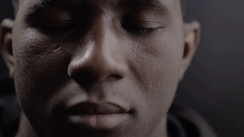 Young black african man with closed eyes,opening and looking at camera Stock Footage 115314815