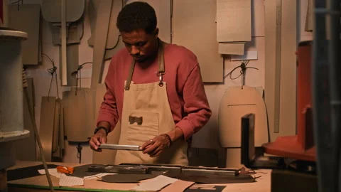 Young Black Artisan Choosing Tools to Work with Leather Stock Footage 299909970