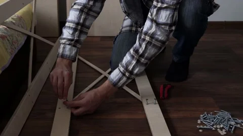 Young Black Bearded Long-haired Man Lays Out Parts Of Bookcase On Floor For Stock Footage 169717922