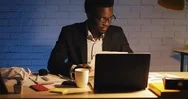 Young Black Businessman With Laptop Computer And Papers Working At Night Office Stock Footage