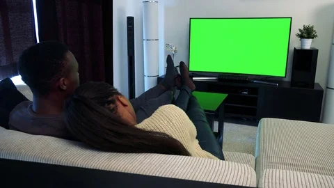Young black couple in love watch television in living room - green screen  Stock Footage