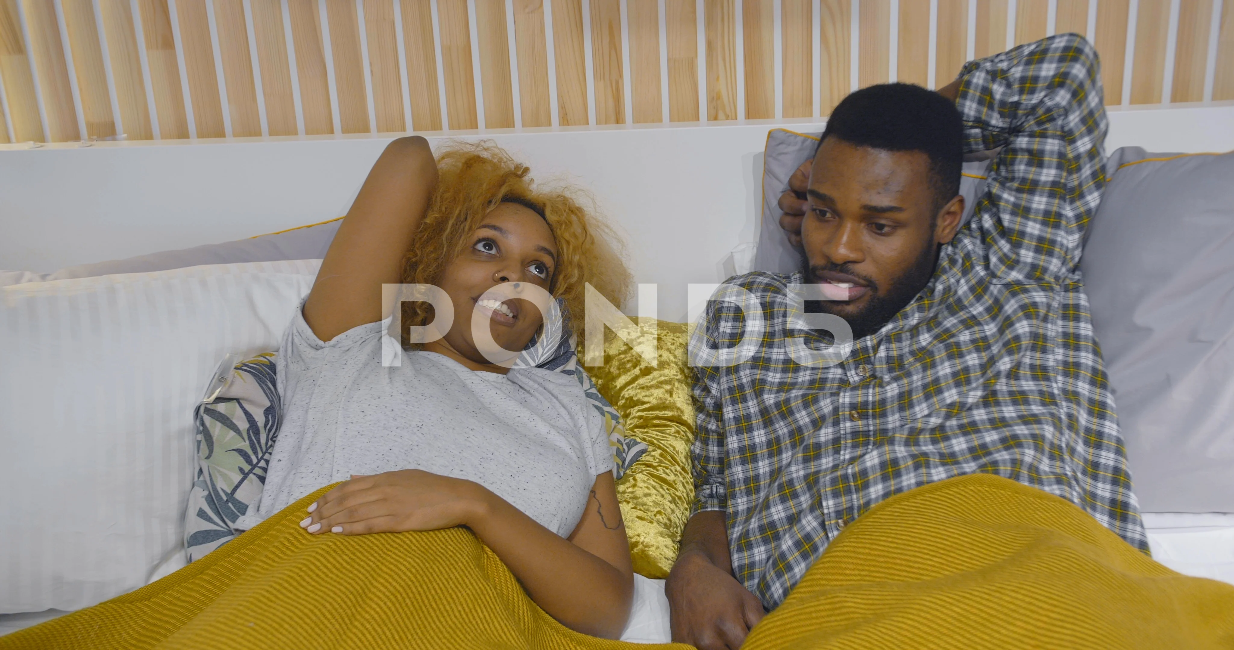 Young black couple lying on bed and talking in bedroom