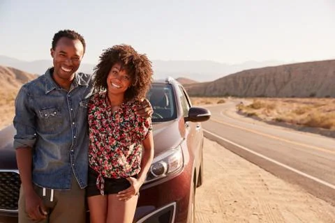 Young black couple standing on desert roadside by their car Stock Photos
