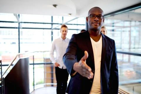 Young black executive facing camera with hand out. Stock Photos