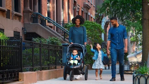 Young black family with stroller walking in Brooklyn street Stock Footage