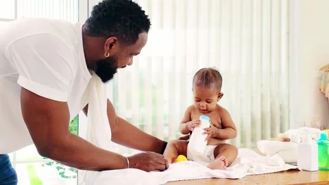 Young Black father lovingly dries and dresses his baby after bath time. Stock Footage 308510573