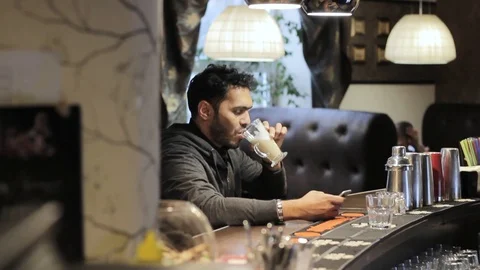 Young black guy in the cafe uses a mobile phone and drinks coffee Stock Footage 85641086