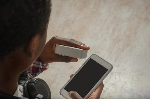 Young black guy connects bluetooth speaker to phone Stock Photos