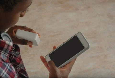 Young black guy connects bluetooth speaker to phone Stock Photos