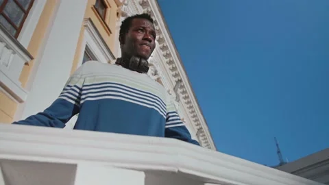 A young black guy poses against the backdrop of a beautiful theater building Stock Footage 155691364