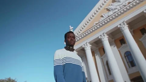 A young black guy poses against the backdrop of a beautiful theater building Stock Footage 155691476