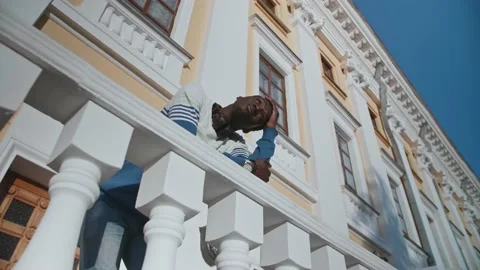A young black guy poses against the backdrop of a beautiful theater building Video stock 155691883