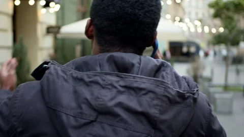 Young Black Guy Walks Down The Street Talking On The Phone. View From The Back. Stock Footage 152032770
