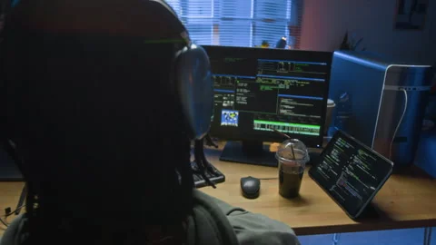 Young Black Male Criminal Coding on Computer at Workstation during Evening Stock Footage 328250366