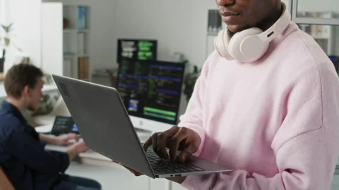 Young Black Male IT Developer with Headset Typing on Laptop in Office 스톡 동영상 330133559
