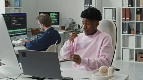Young Black Male IT Engineer Rubbing Eyes while Coding on Computer in Office Stock Footage 330126830