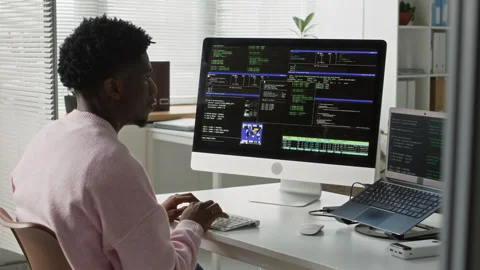 Young Black Male Software Developer Coding on Computers at Office Desk Video stock 330126357