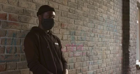 Young black man in black mask standing at street waiting for victim to commit a Stock Footage 263661063
