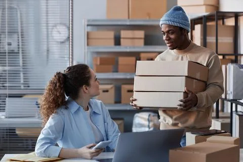 Young black man bringing stack of packed boxes with orders of clients Stock Photos