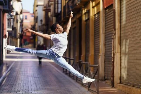 Young black man doing an acrobatic jump in the middle of the street. Stock Photos