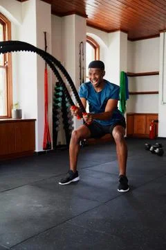 Young black man doing intense cardio workout with battle ropes at the gym Stock Photos