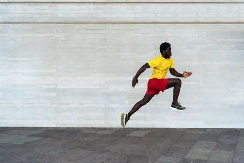 Young black man doing workout routine at morning time while running outdoor - Stock Photos