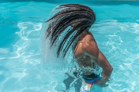 Young black man with dreadlocks inside a pool moving his wet hair. Stock Photos