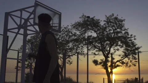 Young black man drinking water while playing basketball on playground on sunrise Stock Footage 160476766