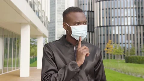 A young black man in a face mask thinks about something - office buildings in Stock Footage 147936032